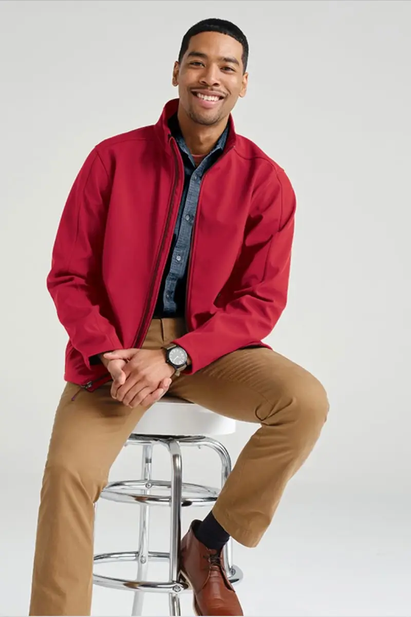 qulity product page 2 A man sits on a chrome stool, wearing a red jacket, denim shirt, tan pants, and brown shoes, exuding a casual, stylish vibe.